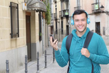 Genç etnik adam dışarıda teknoloji kullanıyor.