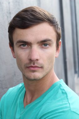 Yakından bakınca, beton duvarın önünde sıradan giysiler içinde yakışıklı bir gencin portresi.