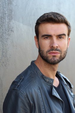 Duvarın önündeki yakışıklı sakallı adamın yakın plan portresi.