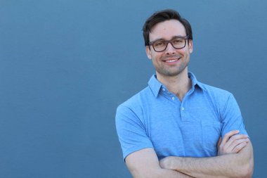 Mavi duvarın önünde sıradan giyinmiş yakışıklı bir gencin yakın plan portresi.