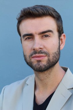 Duvarın önündeki yakışıklı sakallı adamın yakın plan portresi.