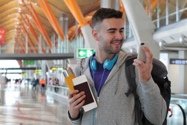 Genç bir adam havaalanından telefon alıyor.