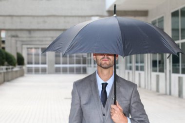 Ofiste şemsiyenin altında saklanan bir iş adamı.