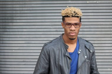 Duvarın önündeki deri ceketli yakışıklı genç adamın yakın plan portresi.