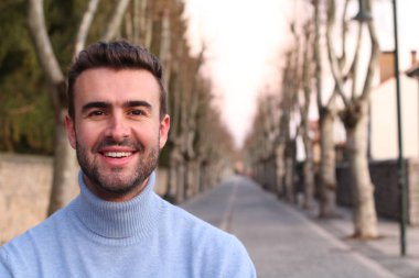 Parktaki balıkçı yaka kazaklı yakışıklı genç adamın yakın plan portresi.