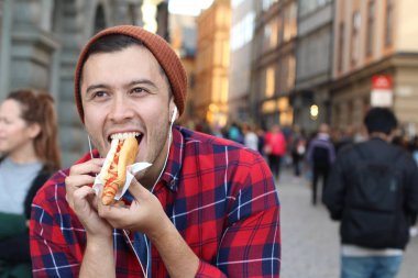 Etnik erkek sosisli sandviç yiyor.