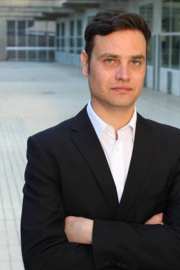 Sokakta siyah takım elbiseli yakışıklı bir adamın yakın plan portresi.