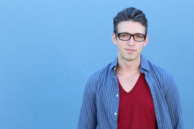 Mavi duvarın önündeki yakışıklı genç adamın yakın plan portresi.