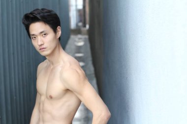 Yakışıklı Asyalı üstsüz bir adamın sokakta çekilmiş yakın plan portresi.