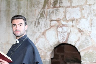 Katedralin önünde kutsal incille genç ve yakışıklı bir rahibin yakın plan portresi.