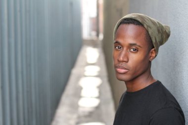 Sokakta siyah tişörtlü yakışıklı Afro-Amerikan adamın yakın plan portresi.