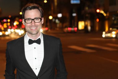 smokinli ve papyonlu yakışıklı bir delikanlının akşam vakti şehir caddesinde yakın plan fotoğrafı.