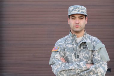 Kahverengi duvardaki yakışıklı genç askerin yakın plan portresi.