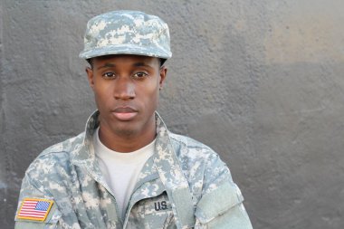 Gri duvarın önündeki yakışıklı Afro-Amerikan askerinin yakın plan portresi.