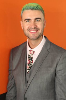 Turuncu arka planda duran yeşil saçlı zarif yakışıklı adam.