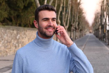 close-up portrait of handsome young man talking by phone on street