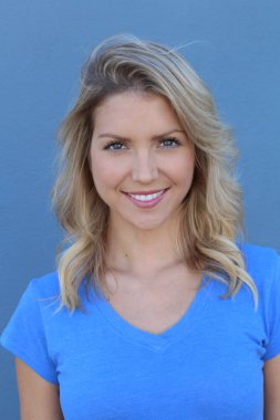 Mavi arka planda gülümseyen güzel sarışın kızın yakın plan portresi.