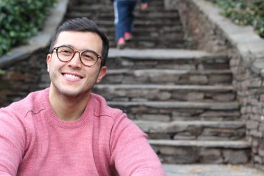 Şehir caddesinde sıradan kıyafetler giymiş yakışıklı bir gencin yakın plan portresi.