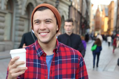 Eski şehir caddesinde tek kullanımlık kahvesi olan yakışıklı bir gencin yakın plan portresi.