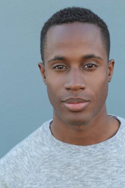 Mavi duvarın önündeki yakışıklı Afro-Amerikan 'ın yakın plan portresi.