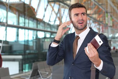 Yakışıklı, takım elbiseli, pasaportlu ve havaalanında uçuş bileti olan genç iş adamının yakın plan fotoğrafı.