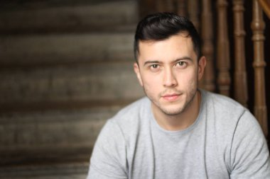 Yakından çekilmiş, sıradan giysiler içinde merdivenlerde oturan yakışıklı bir genç portresi.