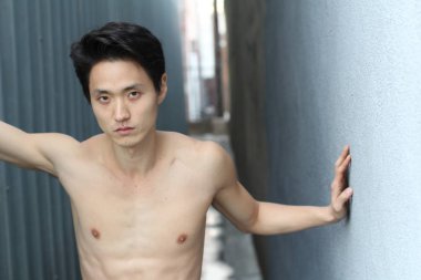 Yakışıklı Asyalı üstsüz bir adamın sokakta çekilmiş yakın plan portresi.