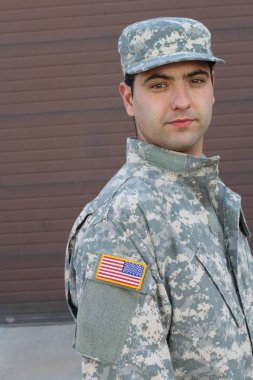 Kahverengi duvardaki yakışıklı genç askerin yakın plan portresi.