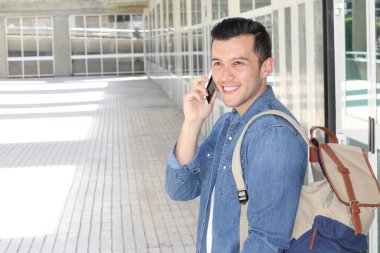 Sokakta telefonla konuşan, günlük kıyafetler içindeki yakışıklı genç adamın yakın plan portresi.