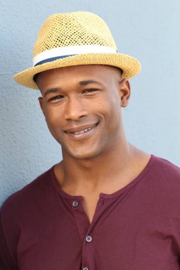 Mavi duvarın önünde şapkalı yakışıklı Afro-Amerikan bir adamın yakın plan portresi.