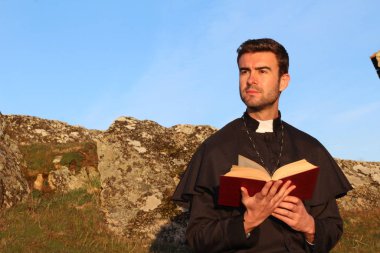 Katedralin önünde kutsal incille genç ve yakışıklı bir rahibin yakın plan portresi.