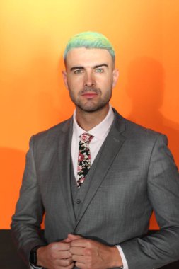 Turuncu arka planda duran yeşil saçlı zarif yakışıklı adam.