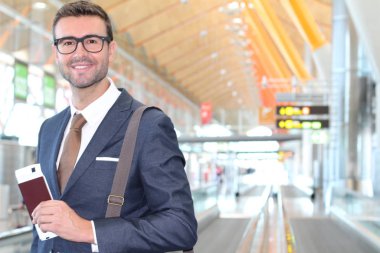 Yakışıklı, takım elbiseli, pasaportlu ve havaalanında uçuş bileti olan genç iş adamının yakın plan fotoğrafı.