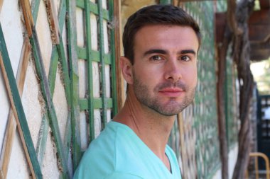 Sokakta duvara yaslanan yakışıklı bir gencin yakın plan portresi.