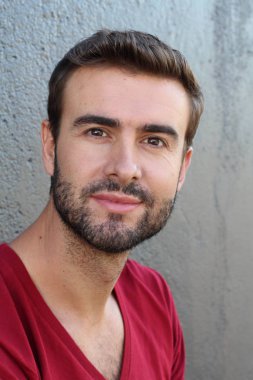 Gri duvarın önündeki yakışıklı genç adamın yakın plan portresi.