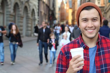 Eski şehir caddesinde tek kullanımlık kahvesi olan yakışıklı bir gencin yakın plan portresi.