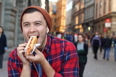 Etnik erkek sosisli sandviç yiyor.
