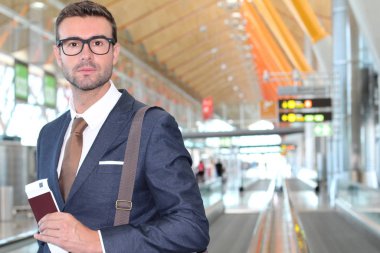 Yakışıklı, takım elbiseli, pasaportlu ve havaalanında uçuş bileti olan genç iş adamının yakın plan fotoğrafı.