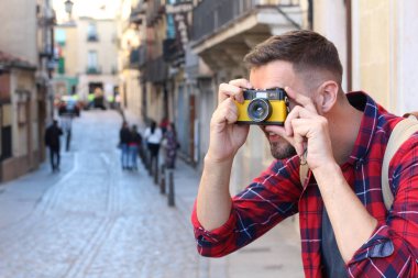 Eski şehir caddesinde sırt çantalı ve klasik kameralı yakışıklı bir gencin yakın plan portresi.