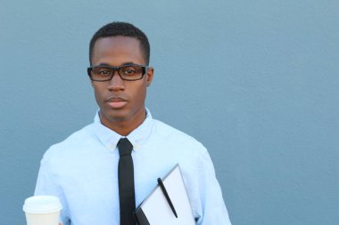 Gri duvarın önünde, üzerinde kravat, dosya ve kağıt kahve olan yakışıklı, Afro-Amerikan iş adamının yakın plan portresi.