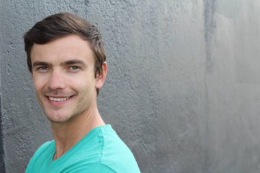 Yakından bakınca, beton duvarın önünde sıradan giysiler içinde yakışıklı bir gencin portresi.