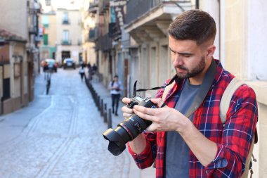 Eski şehir sokaklarında sırt çantalı ve DSR kameralı yakışıklı genç adamın yakın plan portresi.