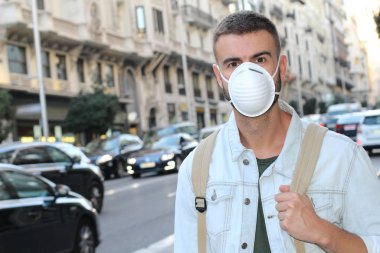 Sokakta tıbbi güvenlik maskesi takmış yakışıklı genç adamın yakın plan portresi.