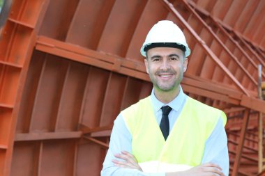 İnşaat alanında koruyucu yelek giymiş yakışıklı bir mimarın yakın plan portresi.