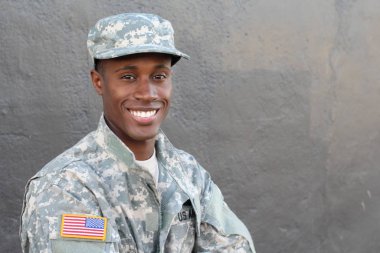 Gri duvarın önündeki yakışıklı Afro-Amerikan askerinin yakın plan portresi.