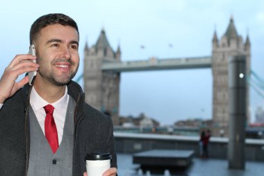 Londra 'daki Tower Bridge' in önünde elinde bir fincan kahveyle yakışıklı genç işadamının yakın plan portresi.