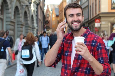 Sokakta elinde kağıt kahve olan yakışıklı bir gencin yakın plan portresi.