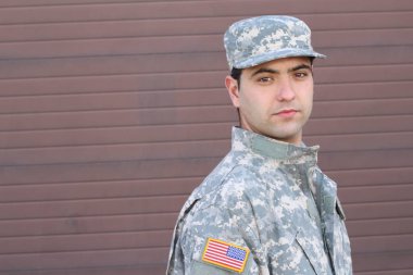 close-up portrait of handsome young soldier in front of brown wall