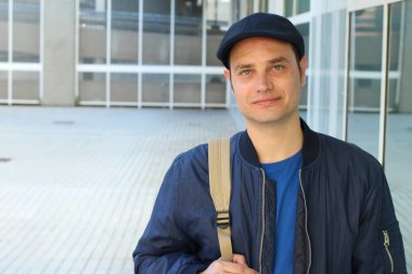 Yakından çekilmiş, sıradan kıyafetler giymiş ve şapkalı yakışıklı genç bir adam portresi.