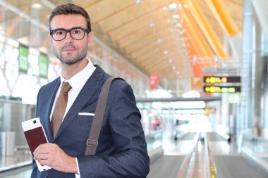 Yakışıklı, takım elbiseli, pasaportlu ve havaalanında uçuş bileti olan genç iş adamının yakın plan fotoğrafı.